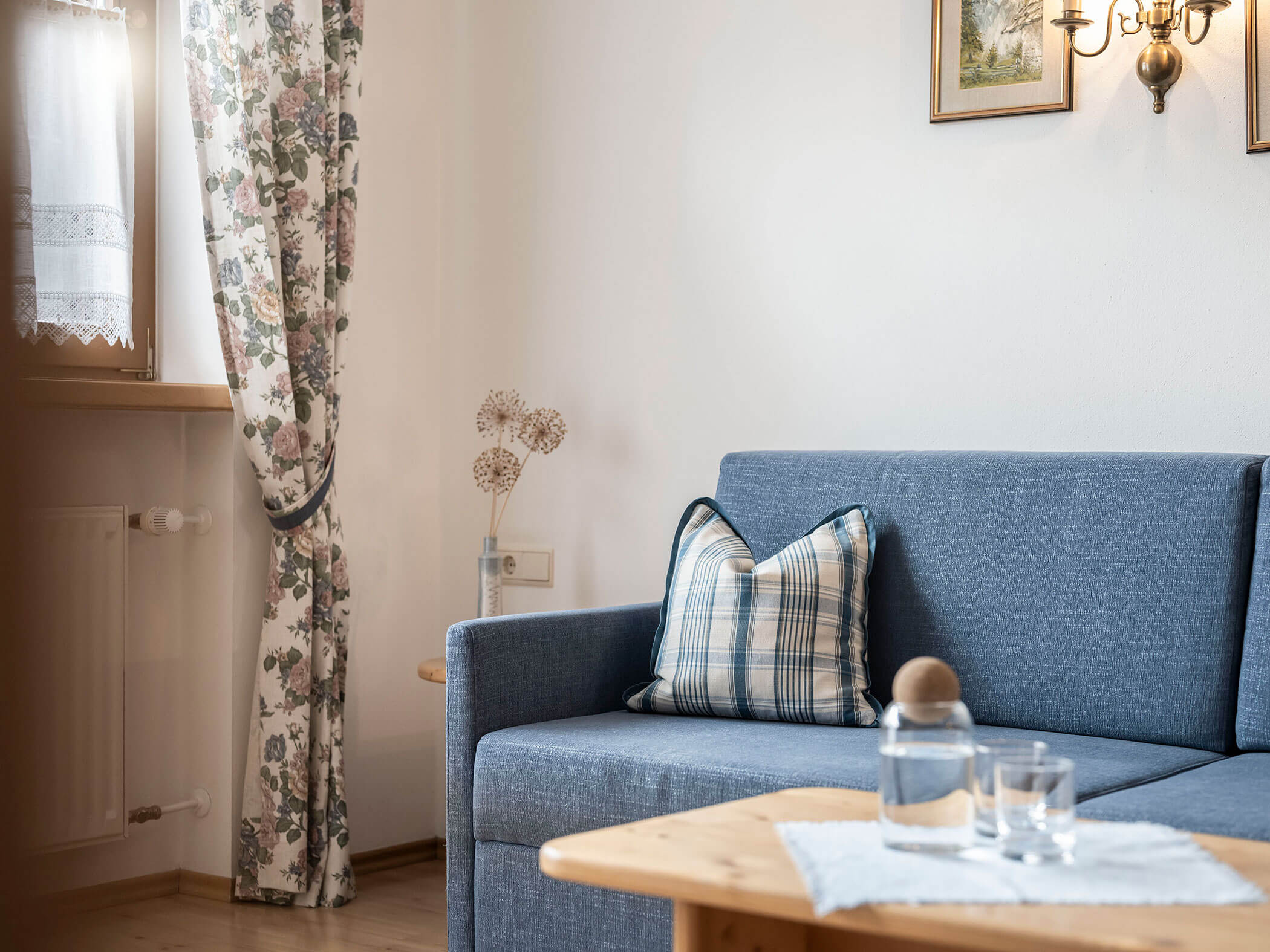 Divano blu con tavolino in legno e caraffa d'acqua nell'appartamento 5 - Residence Kurze Wand