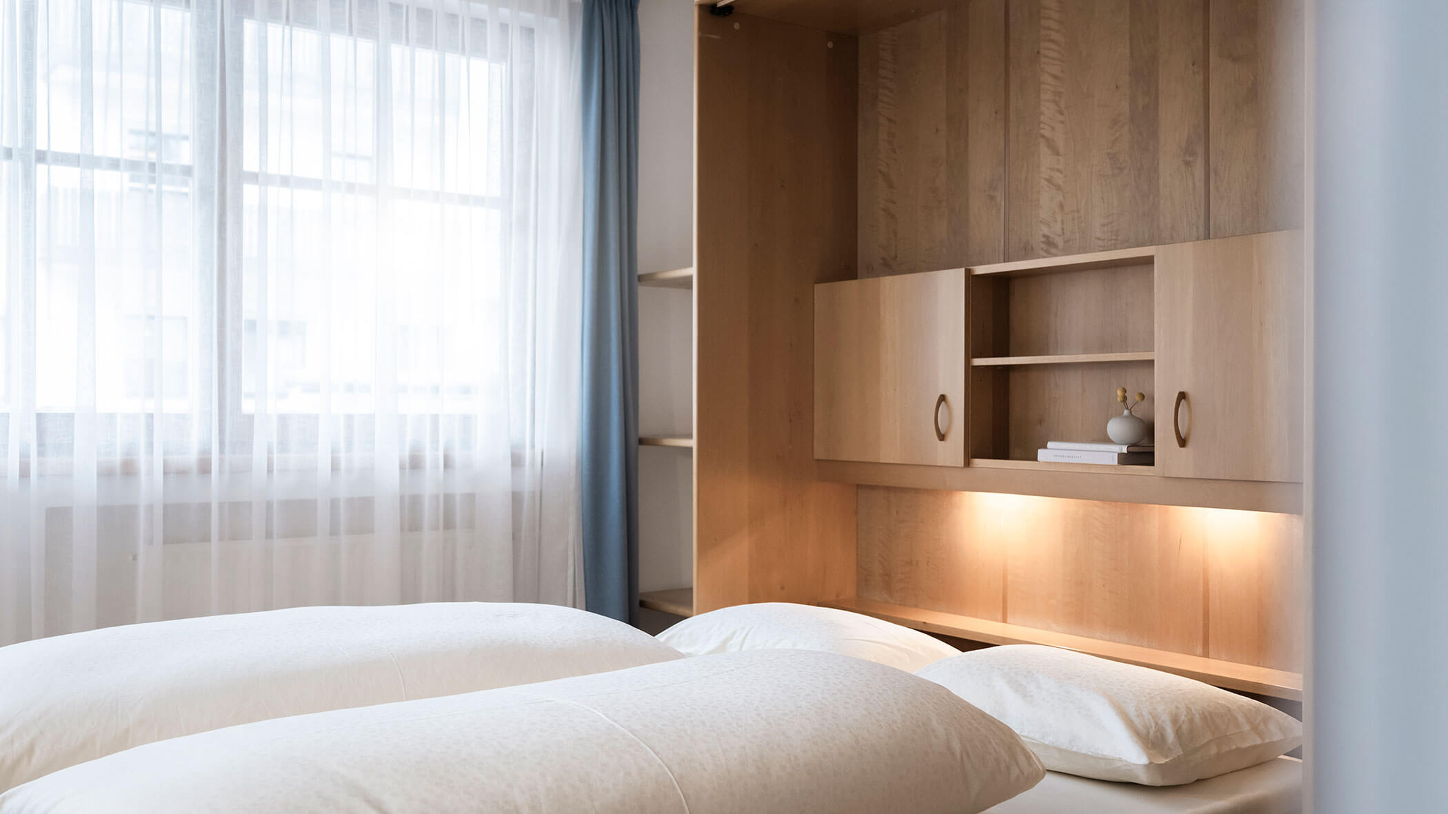 Letto matrimoniale con biancheria bianca e tende blu nell'appartamento 1 - Residence Kurze Wand