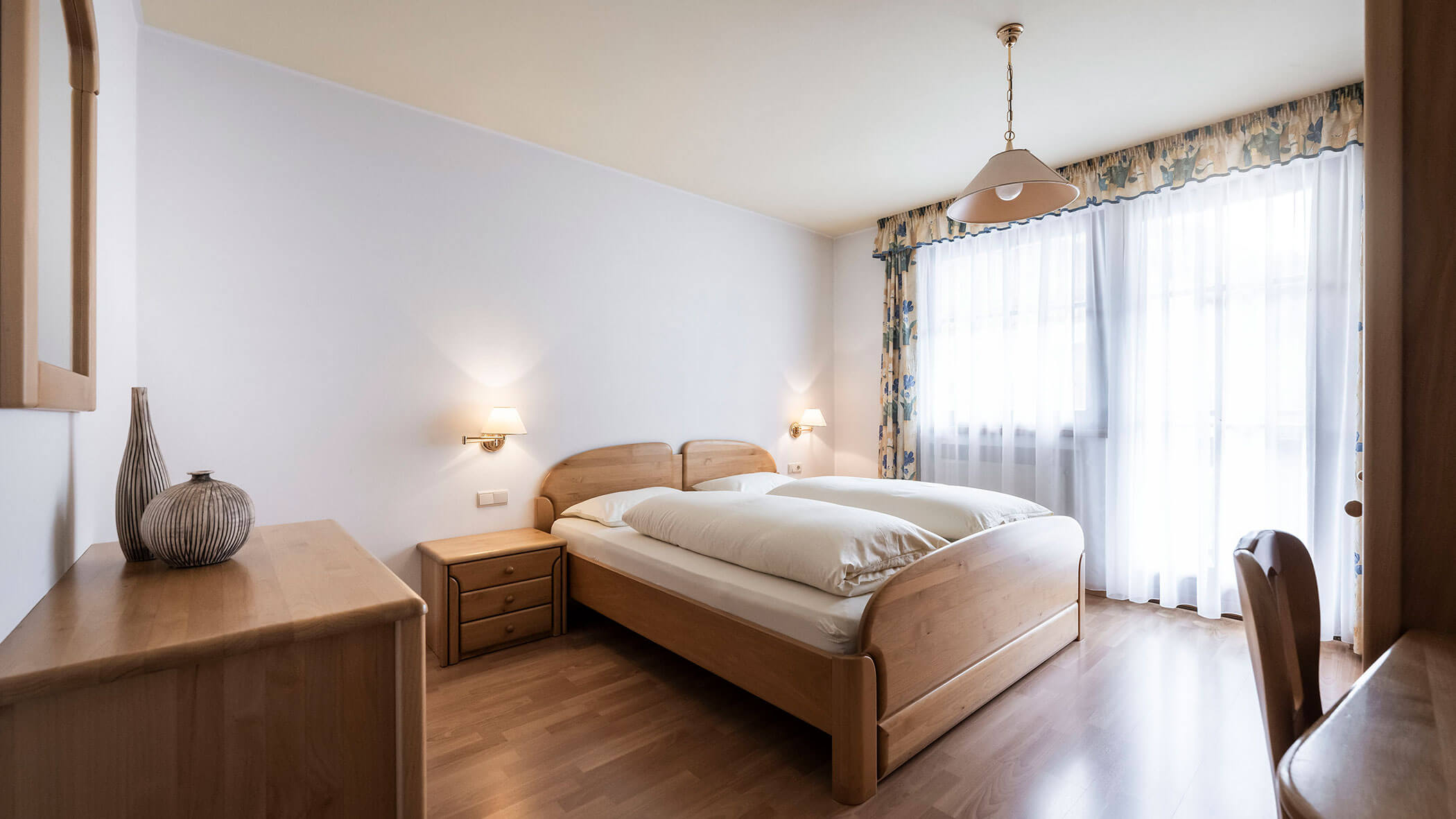 Camera da letto con letto matrimoniale e tende a fantasia nell'appartamento 3 - Residence Kurze Wand