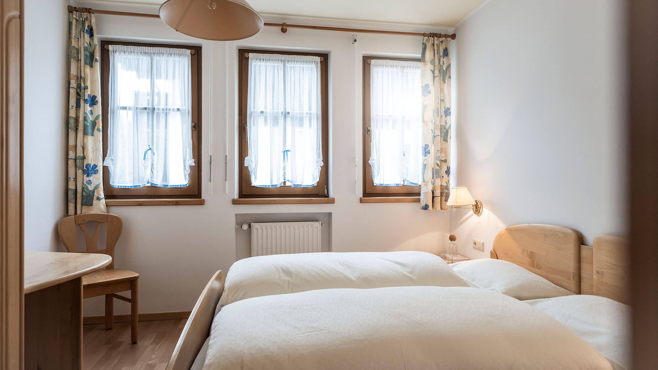 Camera da letto con letto matrimoniale e tre finestre con tende nell'appartamento 4 - Residence Kurze Wand