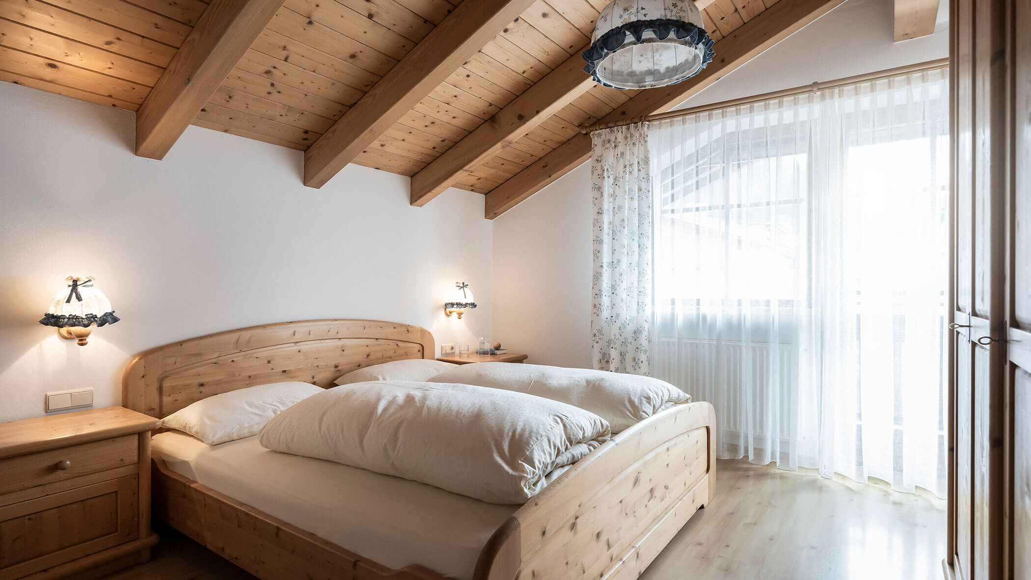 Camera da letto con letto matrimoniale e tende a fantasia nell'appartamento 5 - Residence Kurze Wand