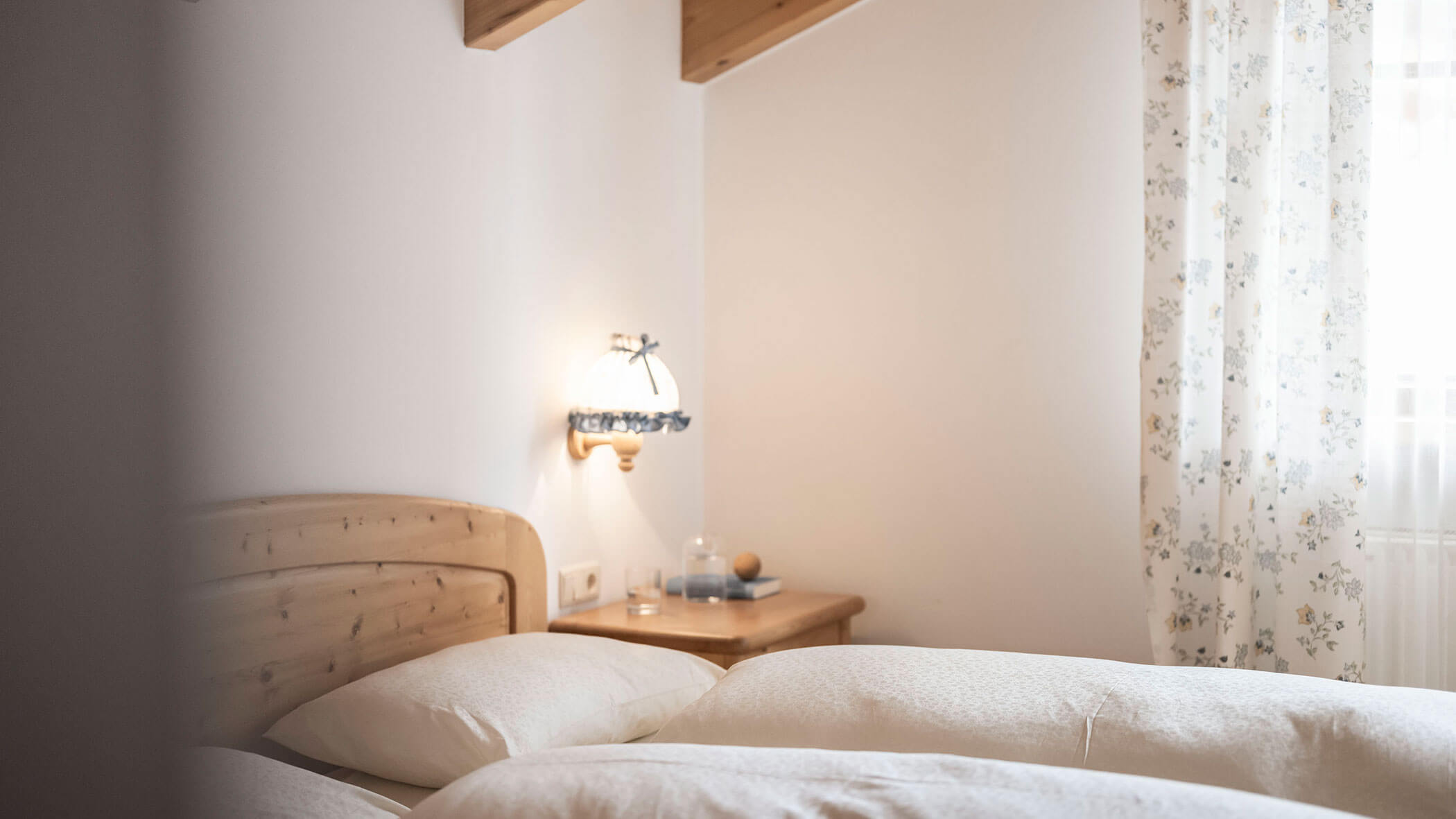 Letto matrimoniale con biancheria bianca e tende a fantasia nell'appartamento 5 - Residence Kurze Wand