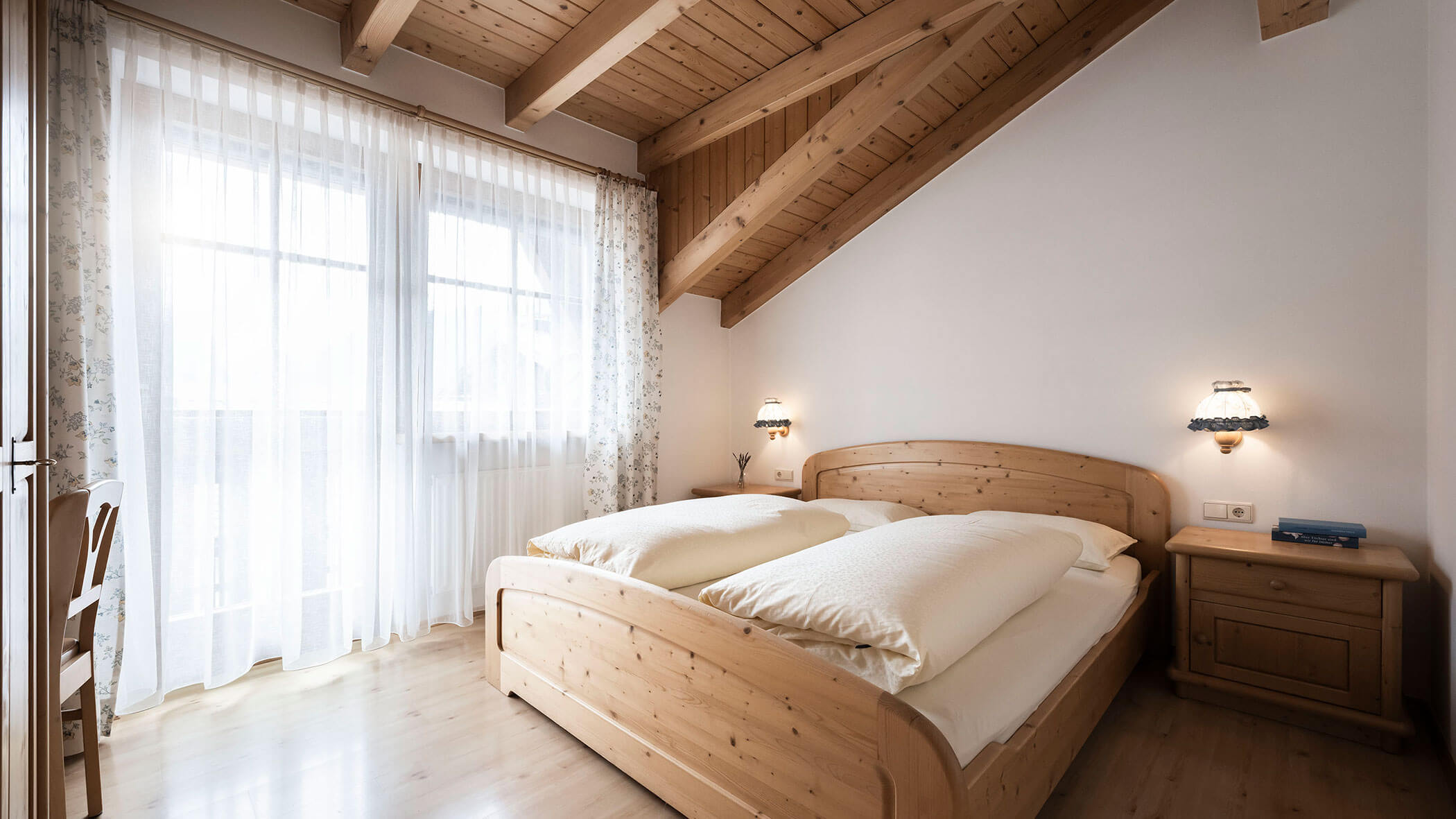 Camera da letto con letto matrimoniale e tende a fantasia nell'appartamento 6 - Residence Kurze Wand