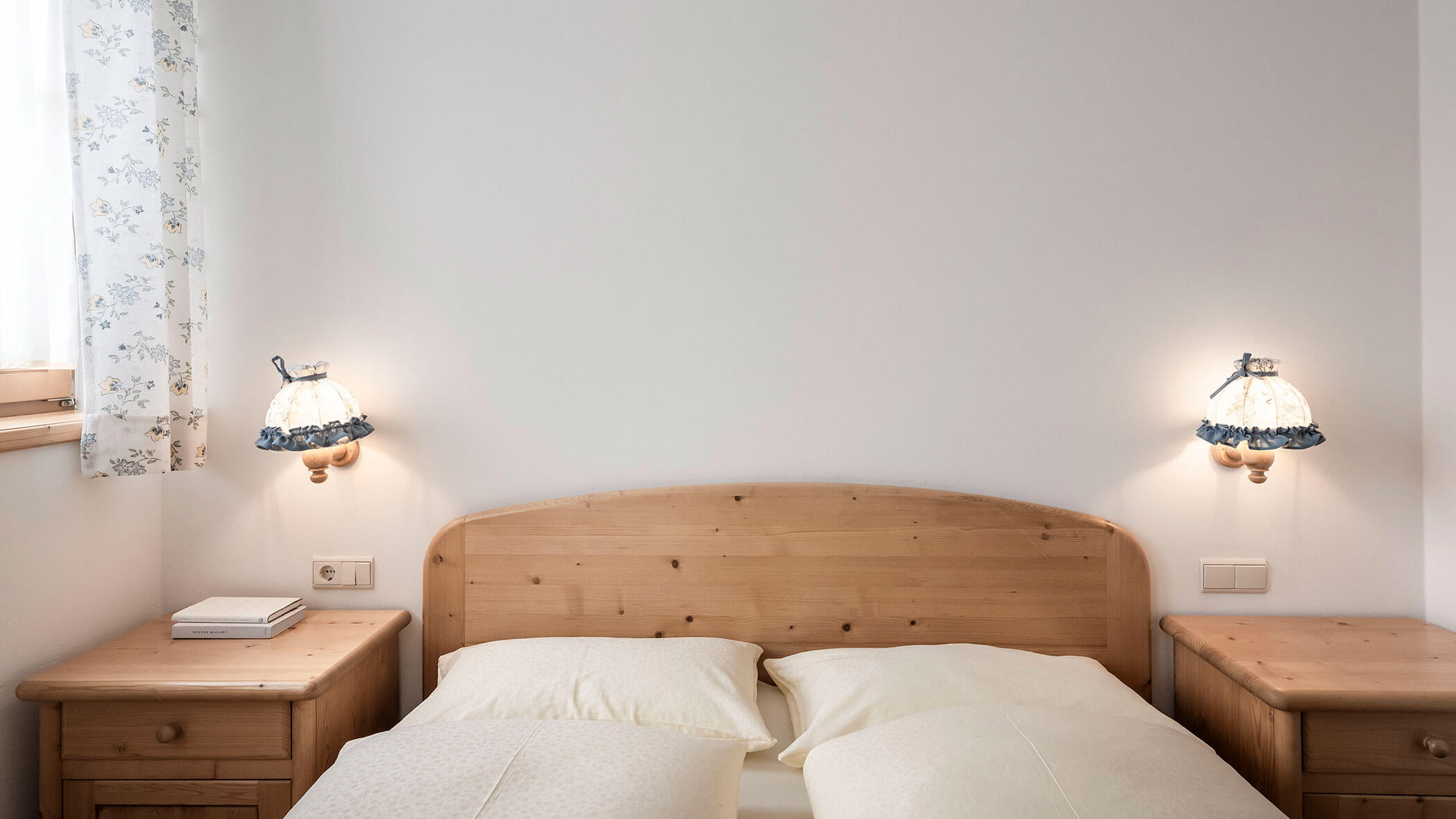 Letto matrimoniale con lenzuola bianche e tende a fantasia nell'Appartamento 6 - Residence Kurze Wand