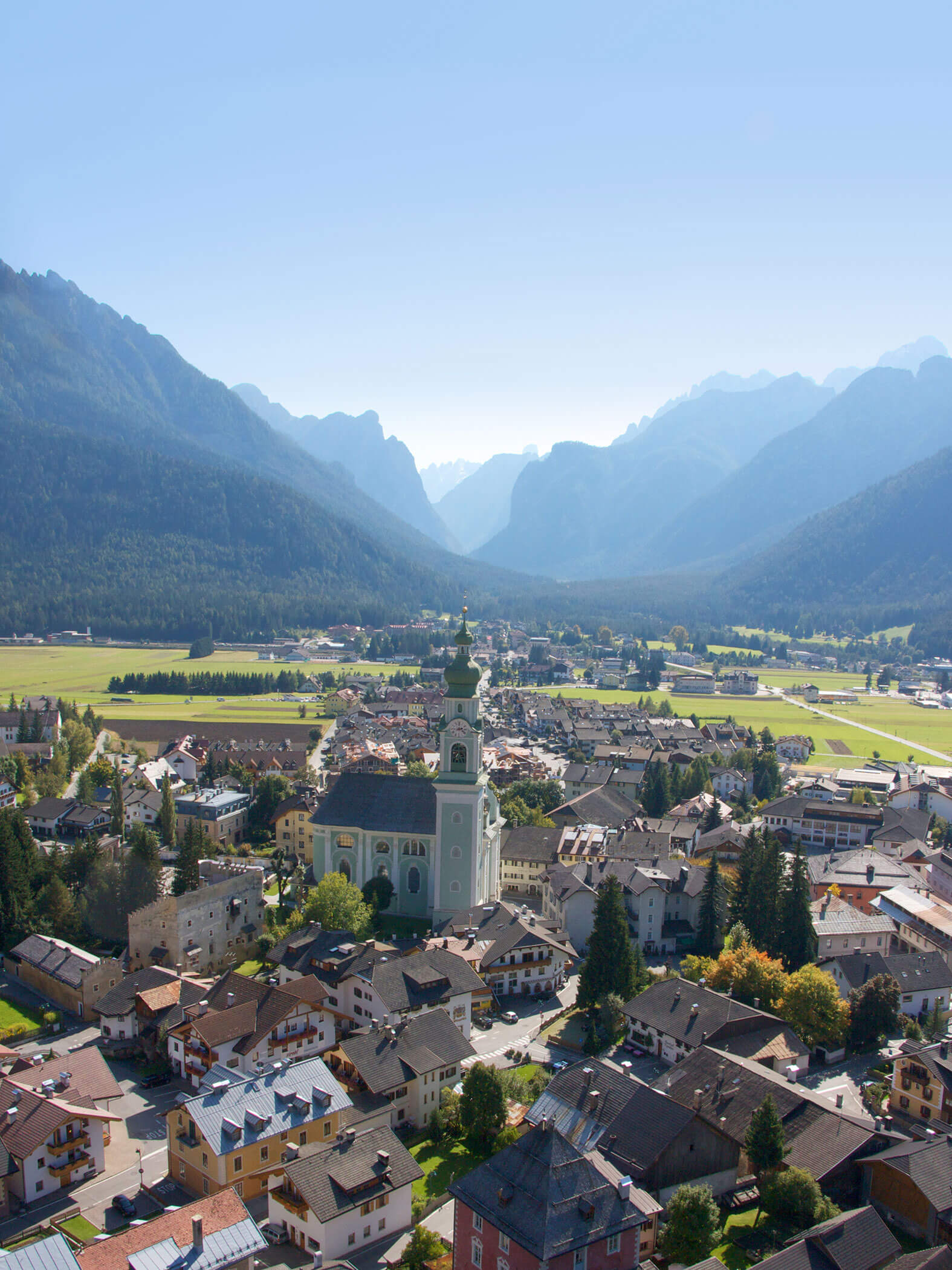 Foto da drone del paese di Dobbiaco con la chiesa in estate - Residence Kurze Wand