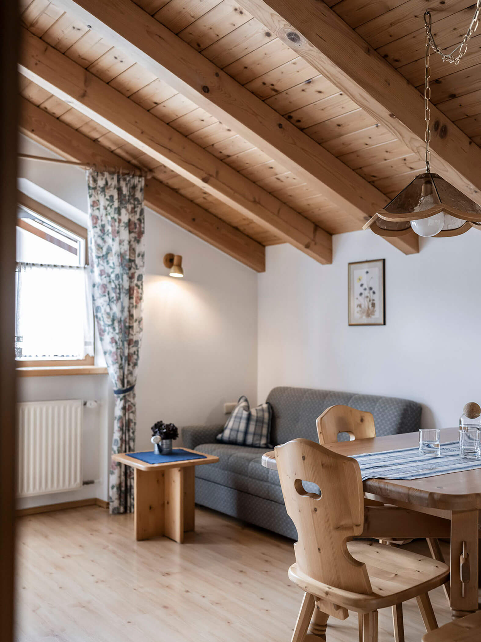 Zona giorno con divano blu e tavolo con due sedie in legno nell'appartamento 6 - Residence Kurze Wand