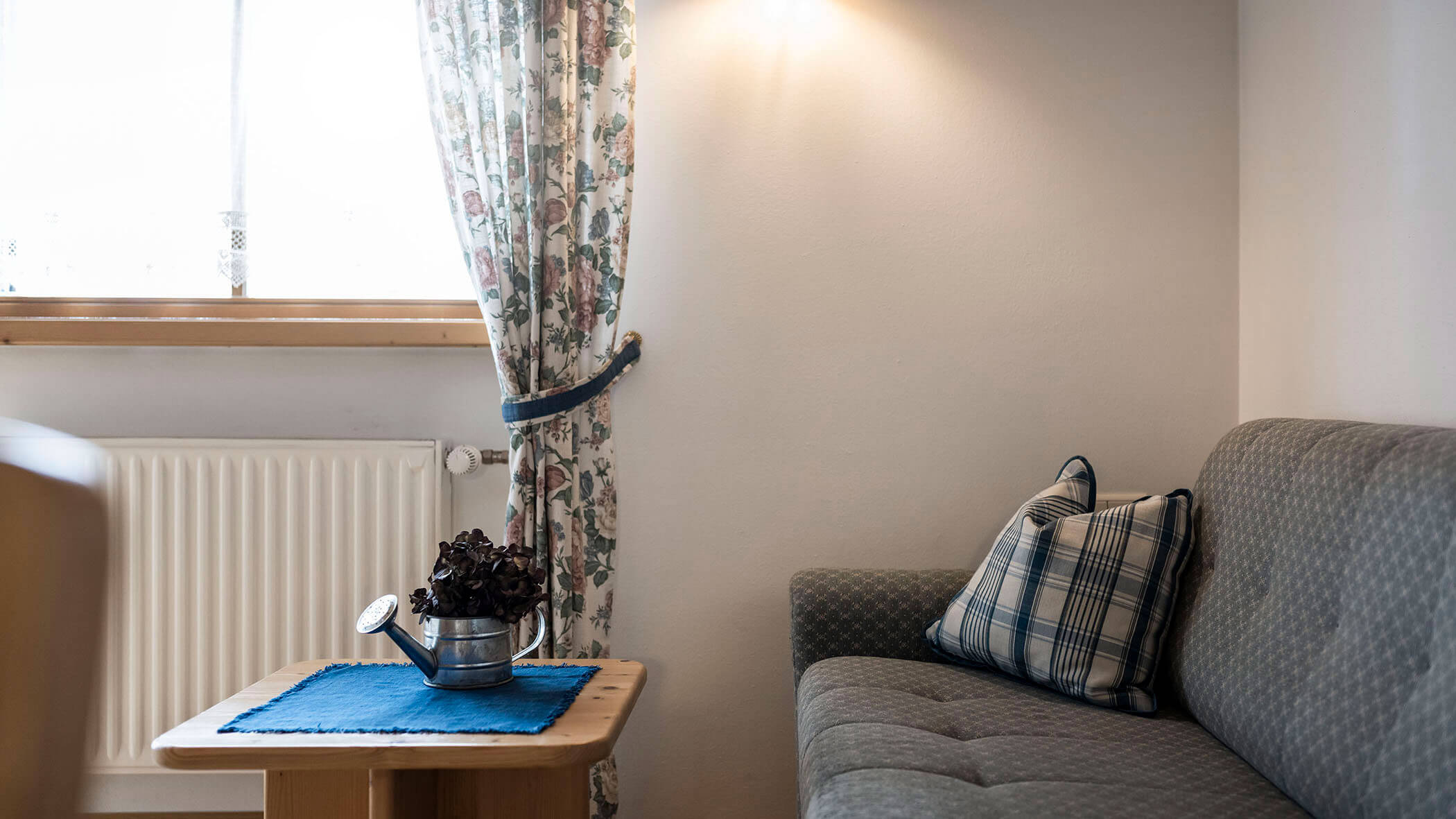 Divano a fantasia blu e tavolino con vaso annaffiatoio - Residence Kurze Wand