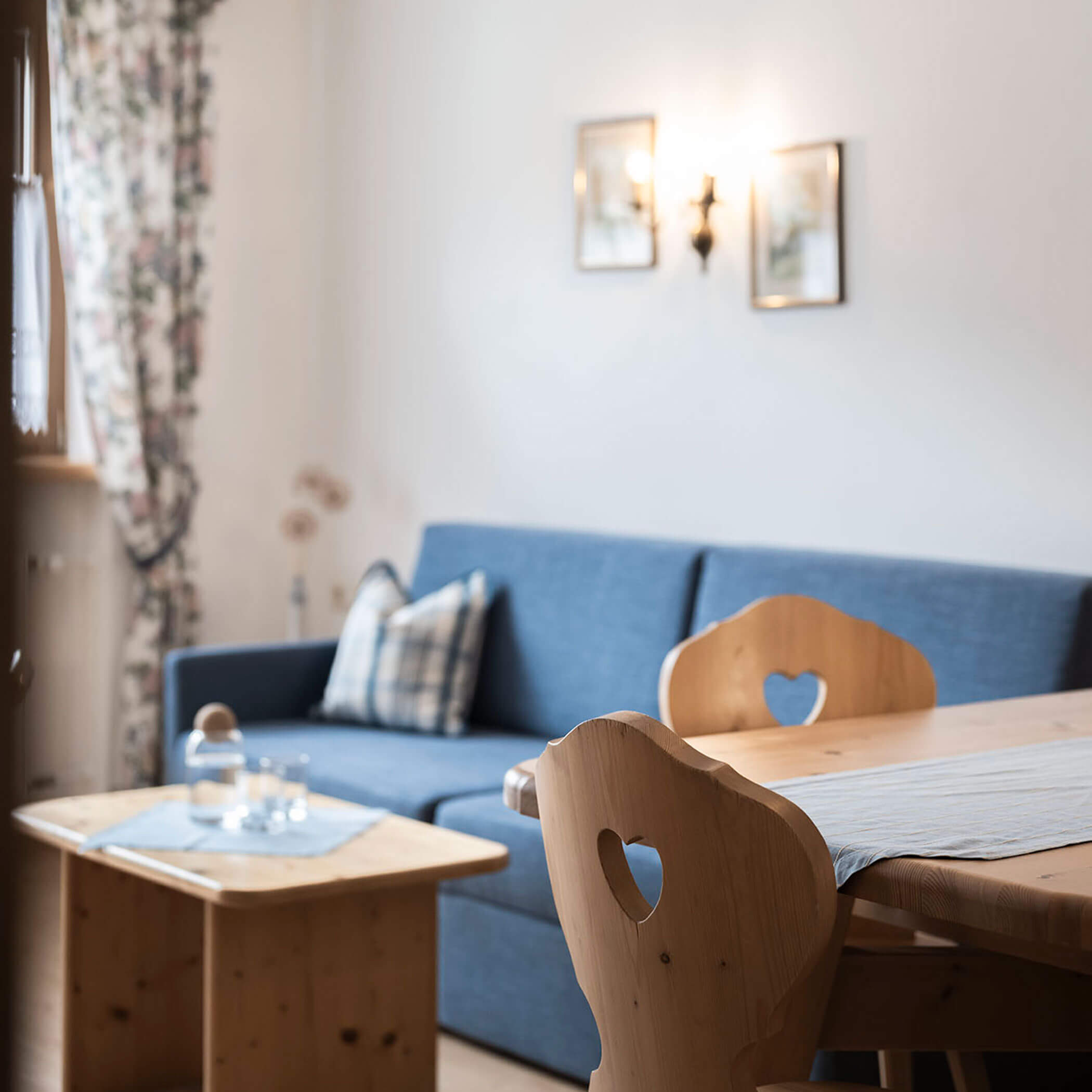 Zona giorno con divano blu e tavolo con due sedie in legno nell'appartamento 5 - Residence Kurze Wand